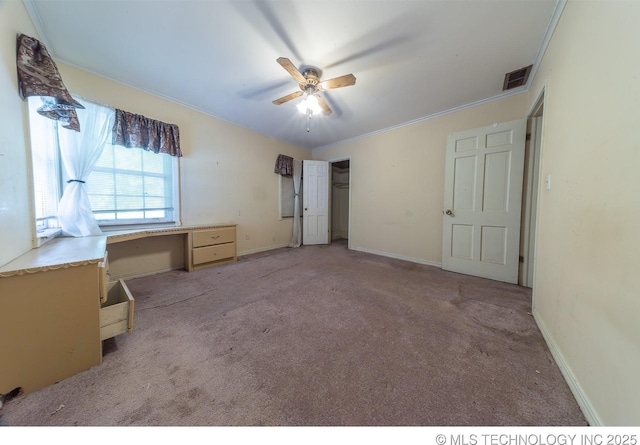 unfurnished bedroom with ceiling fan, built in desk, light carpet, and ornamental molding