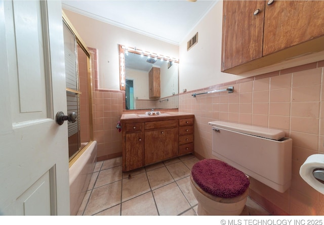 full bathroom with tile patterned floors, crown molding, bath / shower combo with glass door, and tile walls