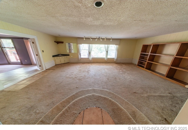 unfurnished living room featuring carpet flooring and a textured ceiling