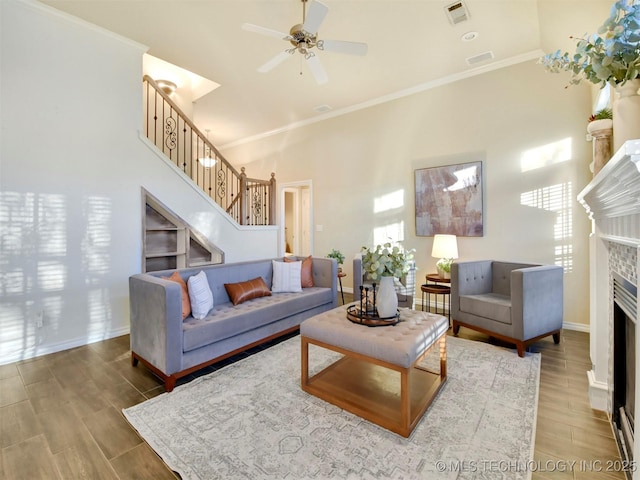 living room with ceiling fan, crown molding, and a tile fireplace