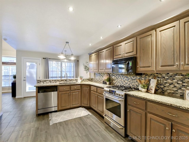 kitchen with sink, stainless steel appliances, tasteful backsplash, kitchen peninsula, and pendant lighting