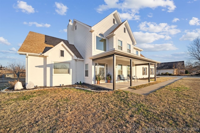 rear view of property featuring a lawn and a patio