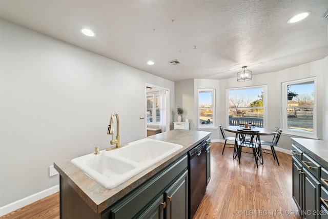 kitchen featuring dark hardwood / wood-style flooring, sink, a center island with sink, an inviting chandelier, and black dishwasher