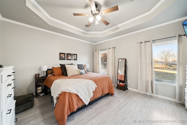 bedroom featuring light wood-type flooring, a raised ceiling, ceiling fan, and crown molding