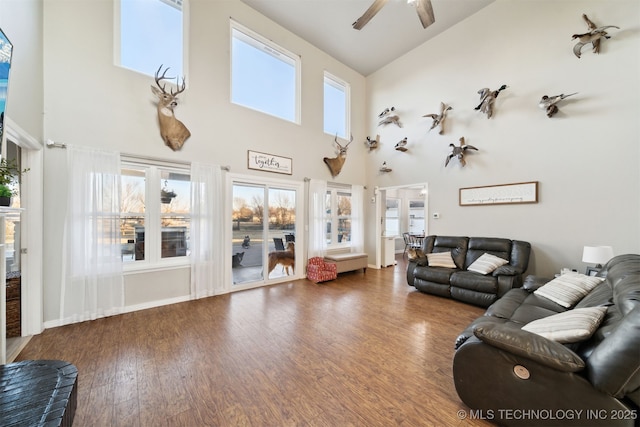 living room with a high ceiling, ceiling fan, and dark wood-type flooring