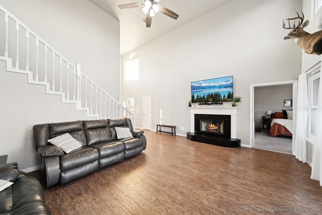 living room with ceiling fan, hardwood / wood-style floors, and a towering ceiling