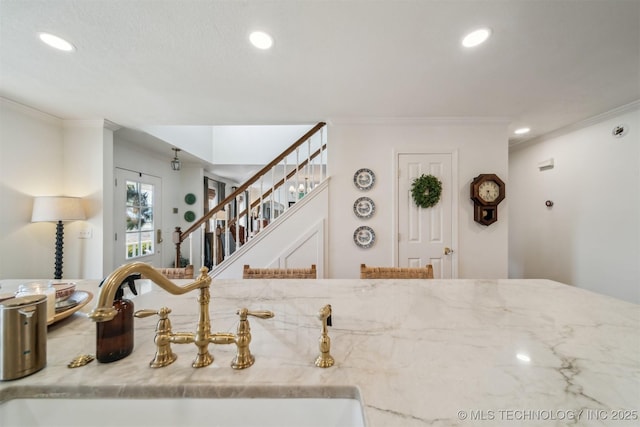 kitchen featuring light stone countertops, crown molding, and sink