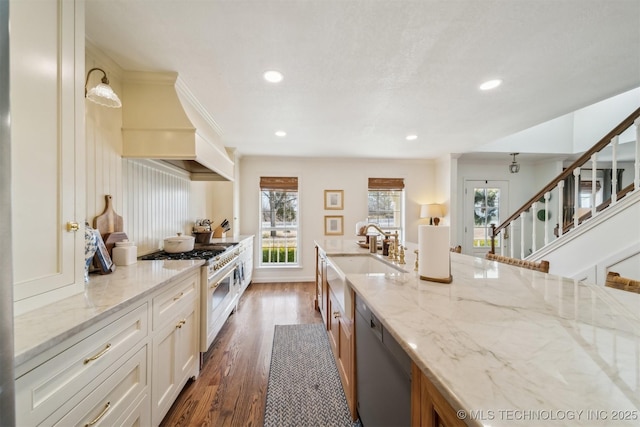 kitchen with sink, hanging light fixtures, light stone counters, dark hardwood / wood-style floors, and appliances with stainless steel finishes