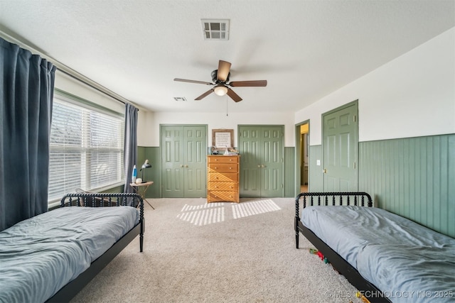 bedroom with ceiling fan, wooden walls, carpet floors, and a textured ceiling