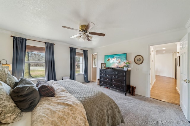 bedroom with a textured ceiling, ceiling fan, ornamental molding, and light carpet