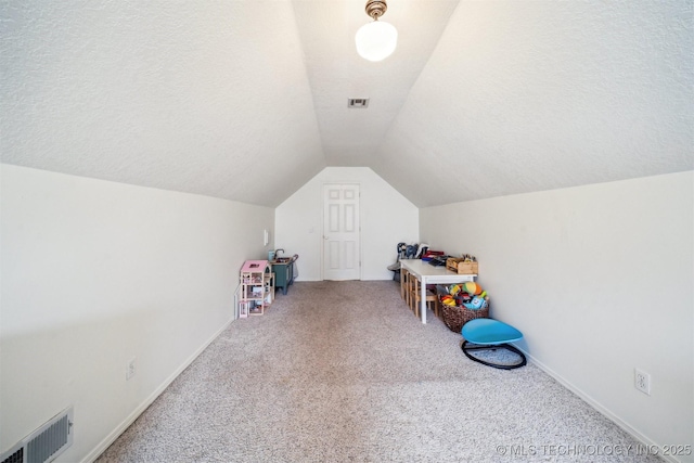 game room featuring a textured ceiling, carpet, and vaulted ceiling