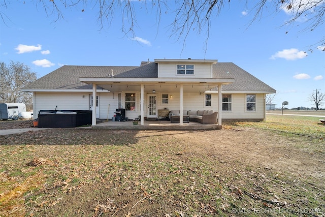 rear view of house with a lawn, an outdoor hangout area, a patio, and a hot tub