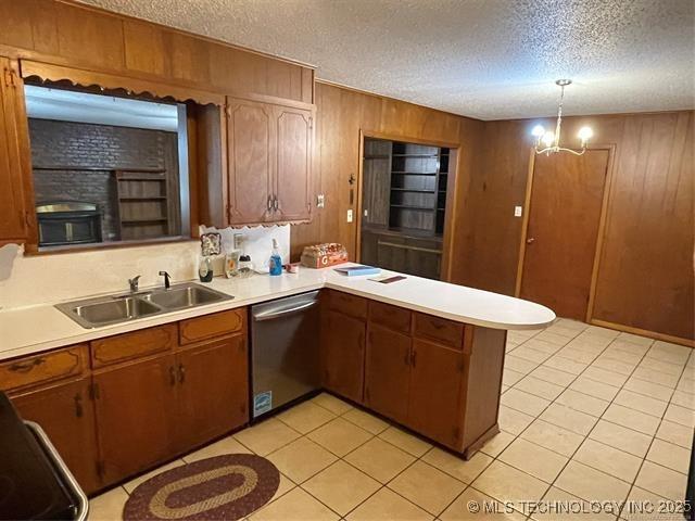 kitchen featuring dishwasher, a textured ceiling, hanging light fixtures, and wood walls