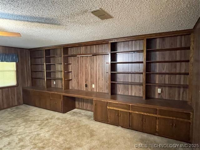 unfurnished office with a textured ceiling, wood walls, and light carpet