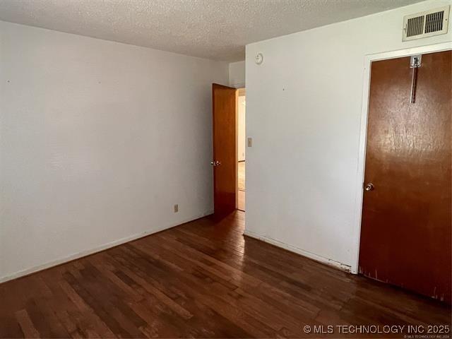 unfurnished bedroom with dark hardwood / wood-style flooring and a textured ceiling