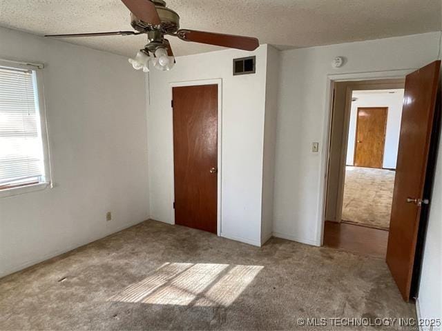 unfurnished bedroom featuring a textured ceiling, ceiling fan, light carpet, and a closet