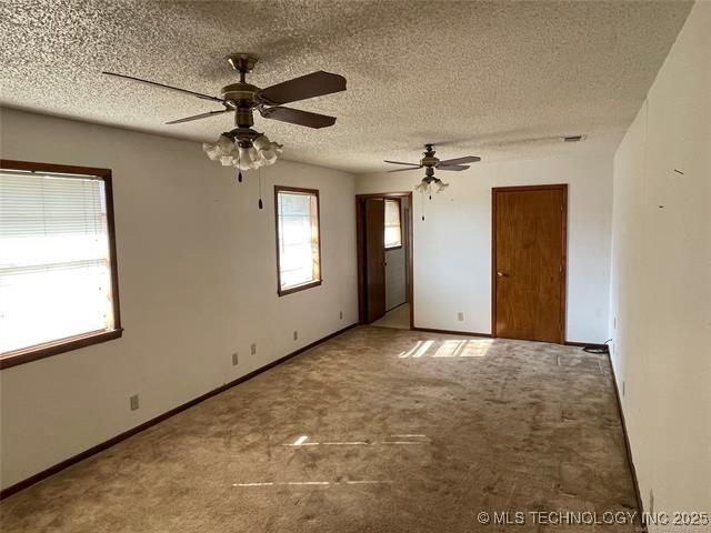 carpeted empty room featuring ceiling fan and a textured ceiling