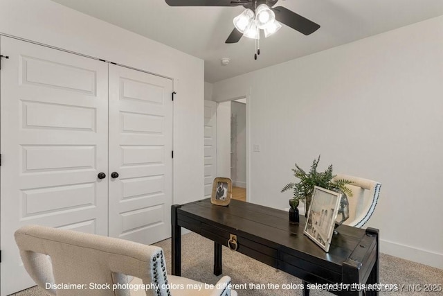 carpeted office space with baseboards and a ceiling fan