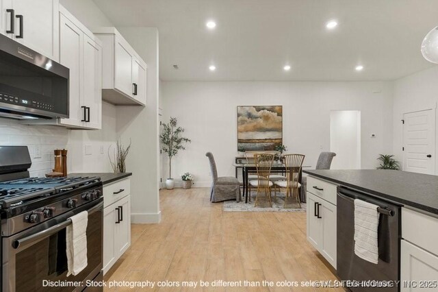 kitchen featuring stainless steel appliances, dark countertops, decorative backsplash, light wood-style floors, and white cabinetry