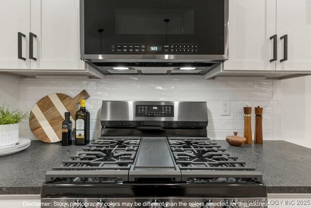 details featuring tasteful backsplash, appliances with stainless steel finishes, dark countertops, and white cabinets