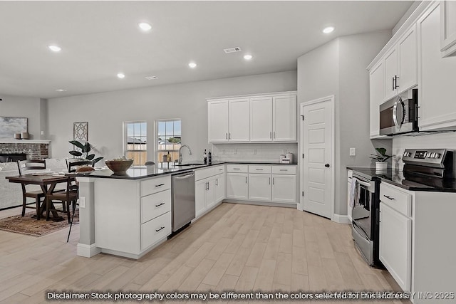 kitchen with dark countertops, stainless steel appliances, a peninsula, and white cabinetry