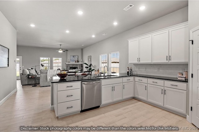 kitchen featuring dishwasher, open floor plan, dark countertops, and a sink