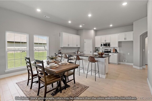 dining room with arched walkways, visible vents, baseboards, and recessed lighting