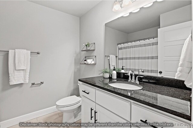bathroom with wood finish floors, baseboards, vanity, and toilet