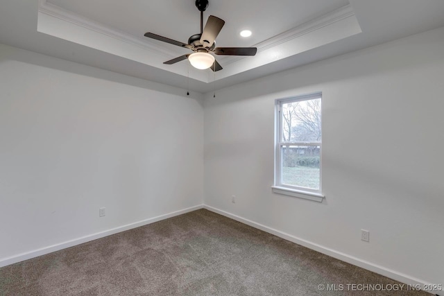 carpeted spare room with ceiling fan, ornamental molding, and a tray ceiling