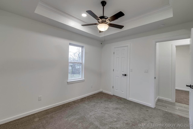 carpeted spare room featuring ceiling fan, a raised ceiling, and ornamental molding