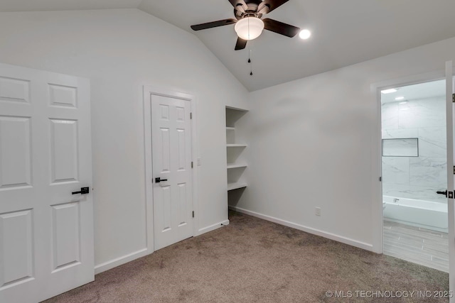 unfurnished bedroom with two closets, ensuite bathroom, vaulted ceiling, ceiling fan, and light colored carpet