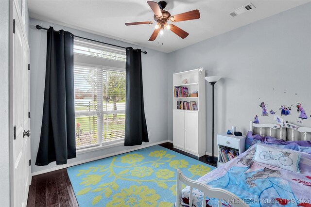 bedroom with ceiling fan, dark wood-type flooring, and multiple windows