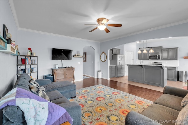 living room with light wood-type flooring, ceiling fan, and ornamental molding