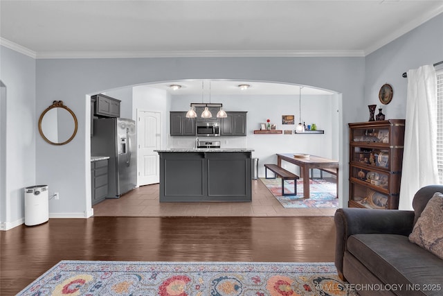 kitchen with dark hardwood / wood-style flooring, light stone counters, stainless steel appliances, gray cabinets, and a kitchen island