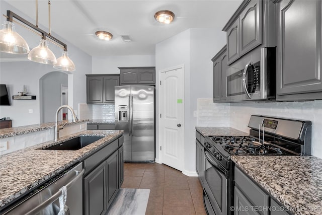 kitchen featuring stainless steel appliances, light stone counters, tasteful backsplash, and sink