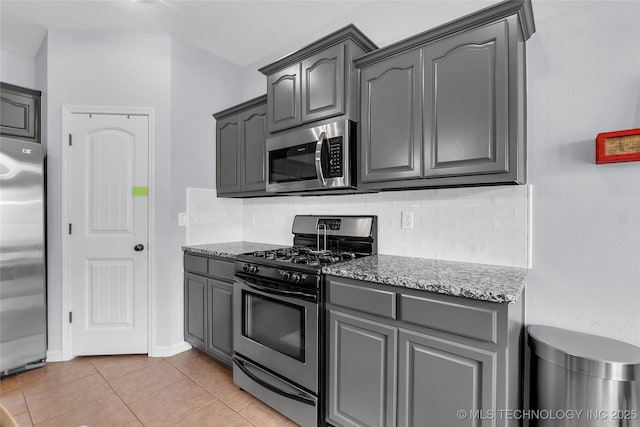 kitchen with gray cabinets, light tile patterned flooring, stainless steel appliances, and tasteful backsplash