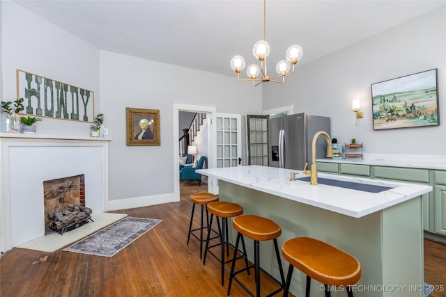 kitchen featuring a kitchen bar, stainless steel fridge, sink, and an island with sink