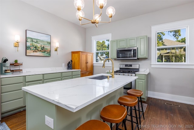 kitchen featuring sink, stainless steel appliances, pendant lighting, a chandelier, and a center island with sink