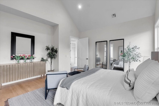 bedroom with wood-type flooring and high vaulted ceiling