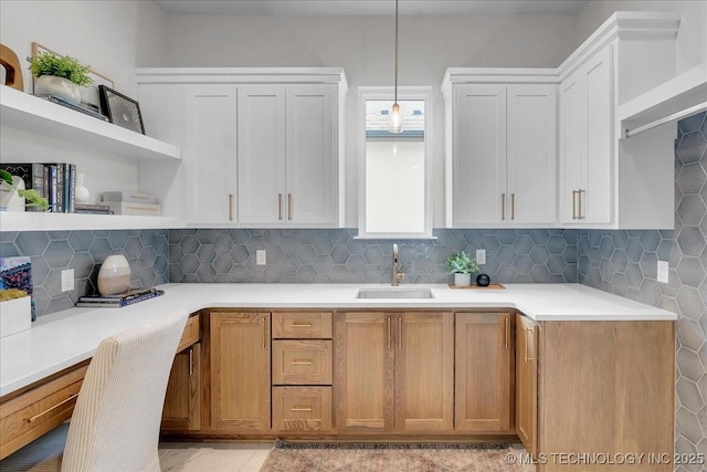 kitchen featuring pendant lighting, sink, tasteful backsplash, and white cabinets