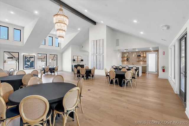 dining space featuring light wood-type flooring, a wealth of natural light, a notable chandelier, and beam ceiling