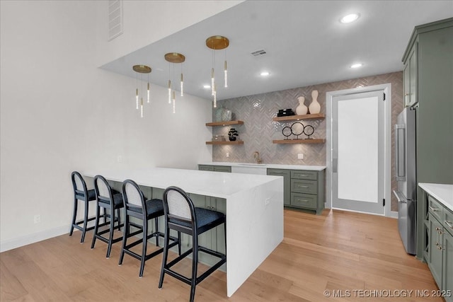 kitchen with a breakfast bar area, hanging light fixtures, tasteful backsplash, kitchen peninsula, and light wood-type flooring