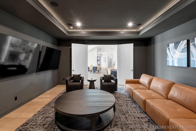 cinema room with crown molding, wood-type flooring, and a tray ceiling