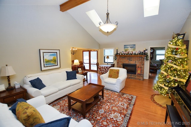 living room with a skylight, a brick fireplace, plenty of natural light, and hardwood / wood-style flooring