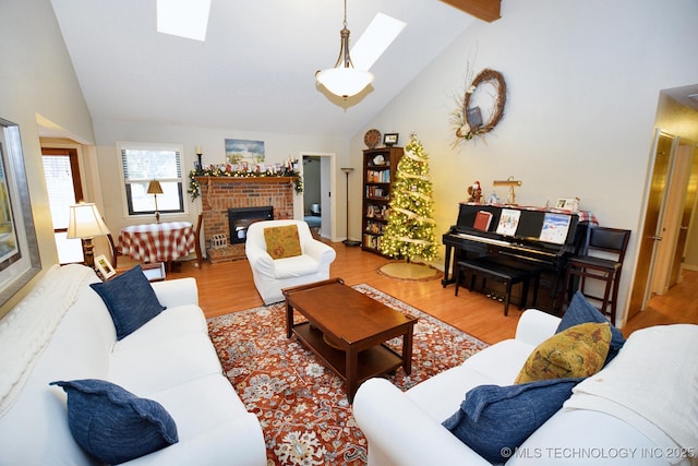 living room featuring vaulted ceiling with skylight, light wood-type flooring, and a fireplace