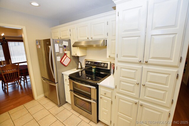 kitchen featuring tasteful backsplash, white cabinetry, light tile patterned flooring, and stainless steel appliances