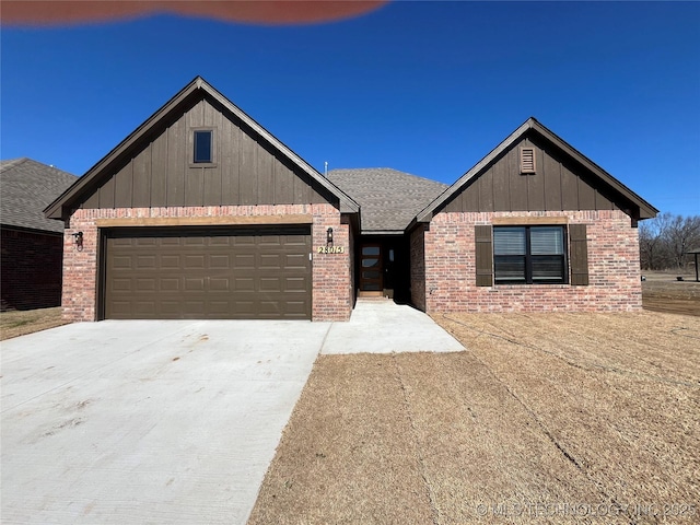 view of front of property featuring a garage, concrete driveway, brick siding, and roof with shingles