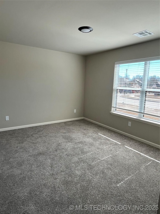 unfurnished room with carpet floors, visible vents, and baseboards