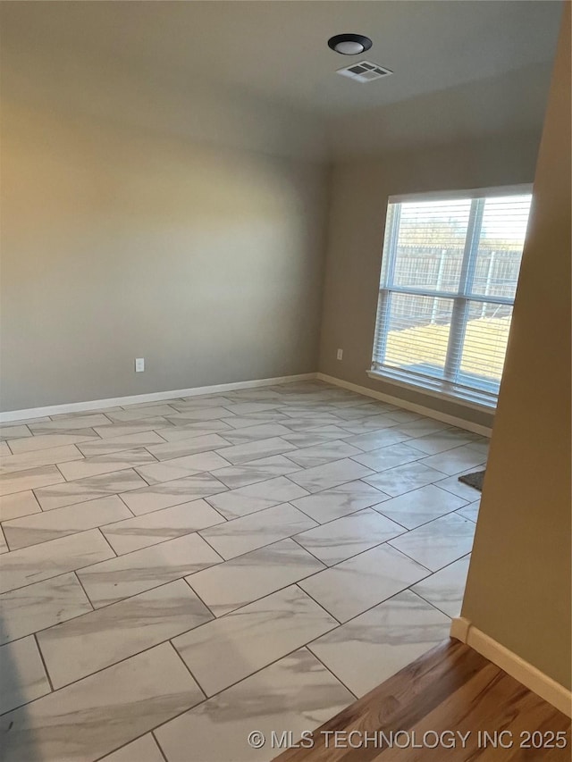 empty room with baseboards and visible vents