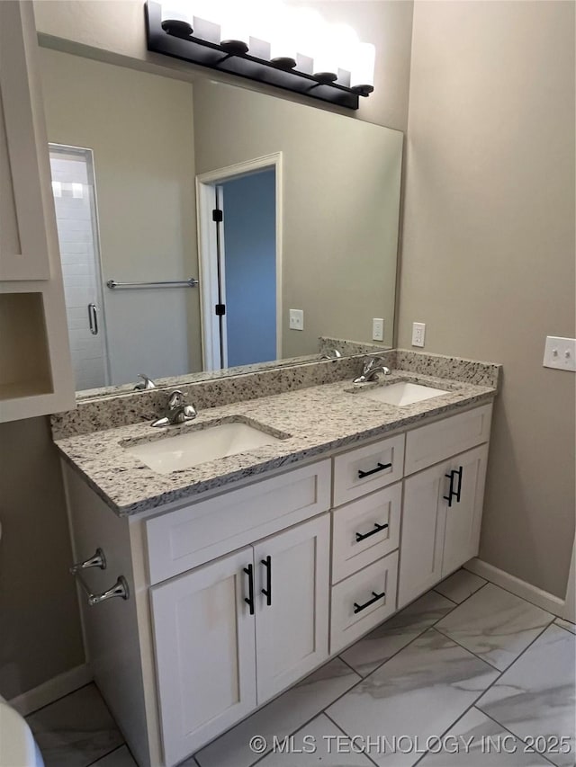 full bath with marble finish floor, a sink, baseboards, and double vanity